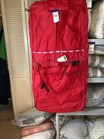 Full view of red garment bag hanging, showing its large size and fabric material.