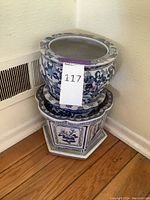 Three Chinese plant pots stacked in corner, showing size difference and design patterns.