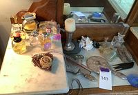 Overview of vanity top showing designer perfumes, pin cushion, bobby pin boxes, hand mirror, brush, and decorative items