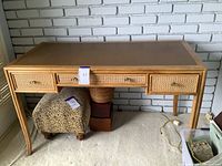 Front view of vintage desk showing three rattan front drawers and metal bamboo-style legs.