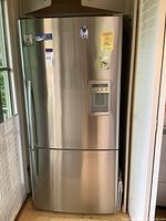 Front view of refrigerator showing brushed aluminum finish, water and ice dispenser, front dents and magnets