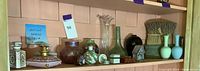Overall shelf view showing multiple ceramic and glass decorative items, including perfume bottles, vases, and trinket boxes.