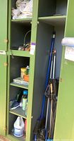 Green cabinet with shelves holding various gardening and household supplies, chemicals, and tools including a broom and drain snake