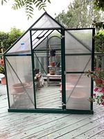 Exterior front view of the greenhouse with door open showing the plants and furniture inside