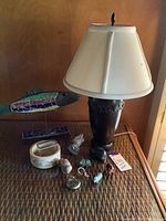 Photo of lamp, mosaic fish sculpture, and assorted small carved items on a woven table