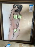 Framed full view of charcoal nude figure drawing depicting a female figure in profile with hands covering face, framed under glass in a light wood frame