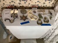 Overview of all jewelry items including earrings, brooches, necklace, watch, and small rings displayed on top of a white surface with floral wallpaper in background.