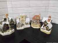Four decorative porcelain houses from David Winter collection with snowy rooftops and detailed textures.