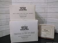 Boxes for Department 56 Heritage Village Collection pieces showing series names and item titles.