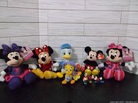 Wide shot showing all plush toys together, characters include Minnie Mouse, Mickey Mouse, Donald Duck, Tweety Bird, and smaller plush toys.