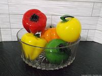 Clear faceted glass bowl holding red, yellow, green, and orange glass vegetables, showing size and color details.