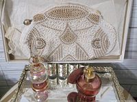 Photo showing white beaded handbag and two vintage perfume bottles on mirrored tray