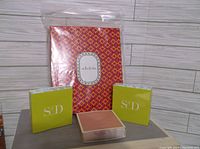 Branded Stella and Dot packaging including a red and orange patterned gift bag and three boxes (two with S/D logo, one smaller pink box)
