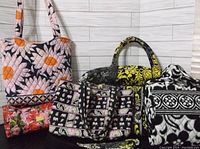 Photo showing three Vera Bradley bags in floral and skull prints and one black-yellow patterned tote alongside a black and white makeup case.