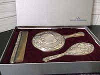 Full view of the vanity set in original Wallace Silversmiths box showing comb, hand mirror, and hairbrush with embossed design.