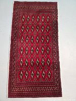 Full view of the rectangular hand knotted Turkmen wool rug with red field and multiple borders.