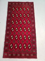 Full view of the rectangular red hand knotted wool rug with repeating geometric patterns, showing the overall design and condition.