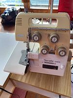 White Bernette 334DS serger sewing machine on wooden board showing front with four thread tension dials and 'electronic' label.