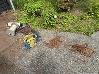 Overall view of the lot showing chains, ropes, pulley, boat cleats and rope holder arranged on driveway with greenery background.