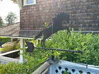 Side view of black metal horse silhouette weathervane showing horse rearing up on hind legs mounted outdoors.