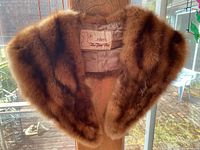 Full view of brown mink stole displayed on a hanger, showing fur texture and satin lining.