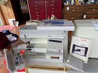 Overall view of Pfaff Creative 1475 CD sewing machine on table with cover and manual to right