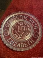 Full view of clear glass plate with embossed text and crest.