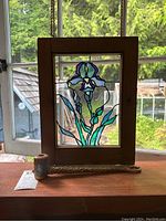 Suncatcher and peace pipe shown on window sill with outdoor view behind