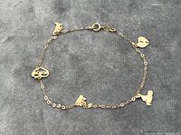 Full view of the gold bracelet laid flat showing all friendship-themed pendants.