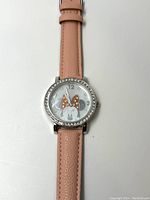 Front view of Disney Minnie Mouse watch with pink leather strap, silver rhinestone bezel, and Minnie Mouse face on dial