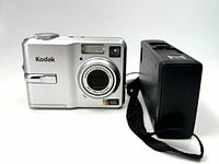 Silver Kodak digital camera with 3x optical zoom lens and built-in flash facing front.