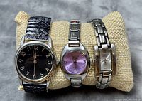 Front view of three ladies watches: Vivani with black dial and strap, Vivani with purple dial and metal bracelet, Isaac Mizrahi Live with rectangular dial and metal bracelet.