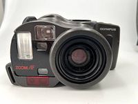 Front view of Olympus Infinity SuperZoom 330 showing lens, built-in flash, red autofocus light, and viewfinder window.