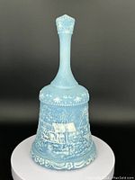 Front view of the Fenton bell showing the full winter scenery in blue opalescent glass with decorative edges.