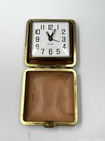 Top view of the open vintage Bulova travel alarm clock showing the clock face and brown interior case lining.