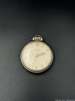 Front view of the pocket watch showing the white dial with Arabic numerals and silver-tone case.