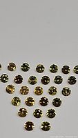 Multiple small round golden yellow diamond cut sapphires arranged in triangular pattern on a flat surface under soft light showing facets and color shading.