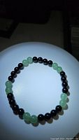 Top view photo showing the round beads alternating between green aventurine and black onyx on a stretchy bracelet.