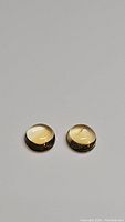 Pair of round golden citrine cabochon gemstones photographed from above on a plain background, showing their smooth domed surfaces and matching color.