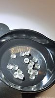 Fourteen round cut natural white topaz gemstones shown in a black container for viewing and sorting.