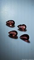 Four pear cut natural garnets with a bright cherry red color on white background, showing clarity and color.