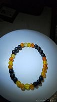 Photo of stretchy bracelet with round yellow agate beads and black lava stone beads under spotlight.