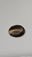 Front view showing the oval cut and faceting of the natural smokey quartz gemstone with translucent dark brown color.
