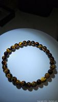 Top view of natural tigerseye stretchy bracelet showing round polished beads with natural golden-brown chatoyant patterns.