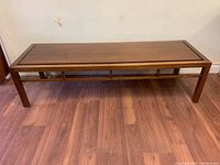 Full frontal view of walnut rectangular coffee table showing top and legs on hardwood floor.