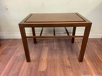 Front view of walnut magazine accent table on wood floor showing rectangular top and magazine rack underneath
