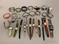 Overhead photo showing 22 assorted wristwatches laid out on white background. Various styles, band types and colors visible.