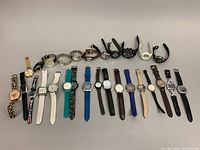 Overall view of 20+ assorted watches with various strap materials, dial shapes, and colors. Includes leopard print, leather, metal, and silicone strap watches.