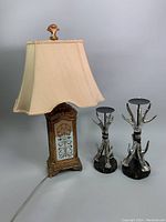 Photo showing the Art Deco style mirrored lamp with cream fabric shade and the two silver-tone antler pillar candleholders of different heights on a white background.