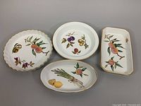 Photo of four vintage porcelain Royal Worcester EVESHAM serving pieces showing fruit and vegetable decorations with gold trim.